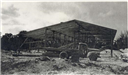 Black and white photo of a truck parked in front of a warehouse's erected frame