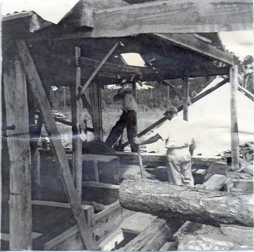 Black and white photo of two men working in a saw mill