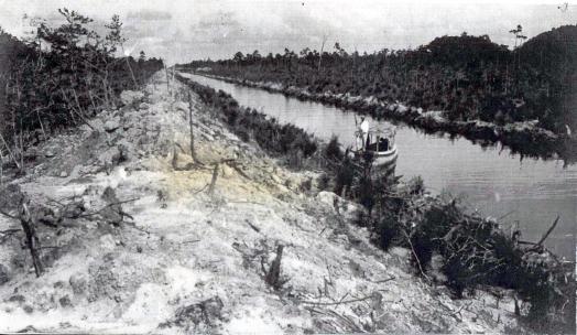 Black and white photo of a person in a row boat in the canal
