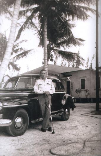 Black and white photo of Elisha Jarriel standing by his car, circa 1940s